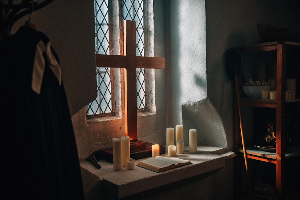 a cross, a book, candles, and a book on a window sill