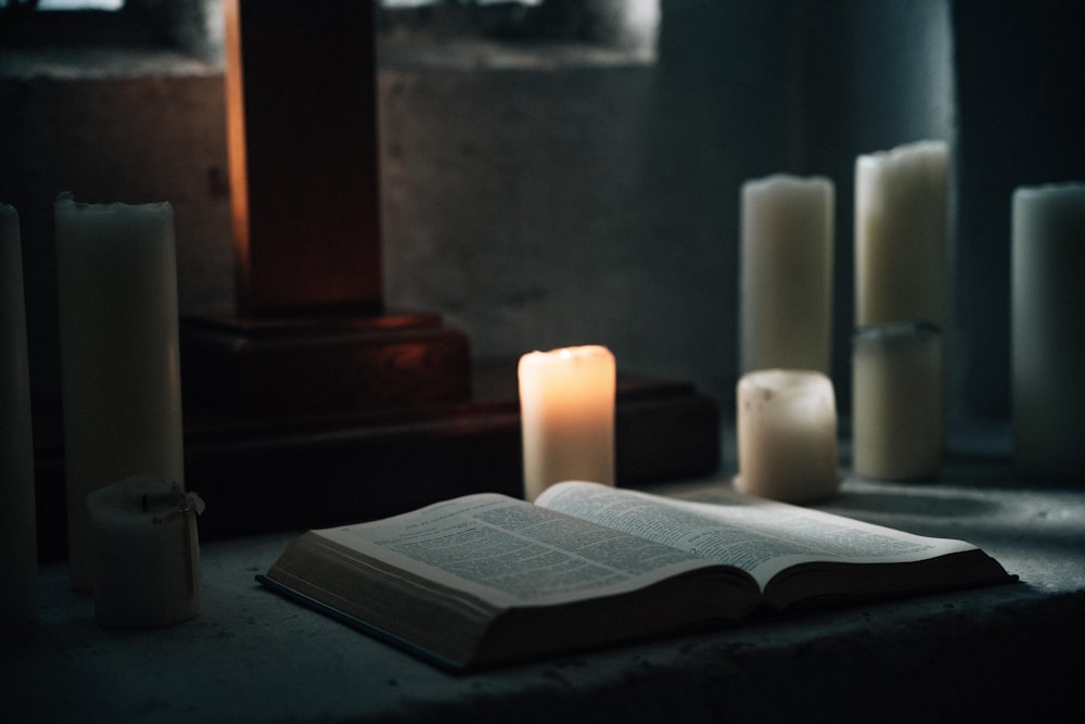 an open book sitting on top of a table next to candles