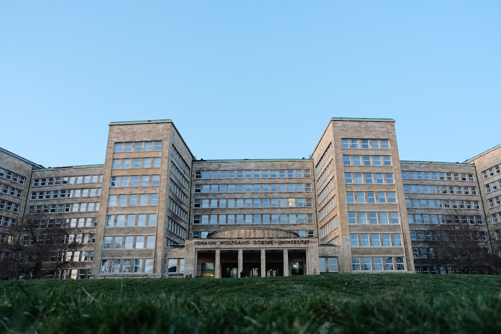 a large building with many windows and a grassy area in front of it