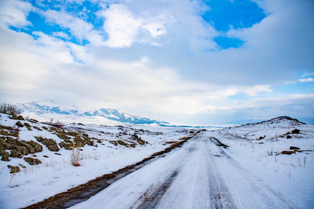 a snow covered road with mountains in the background