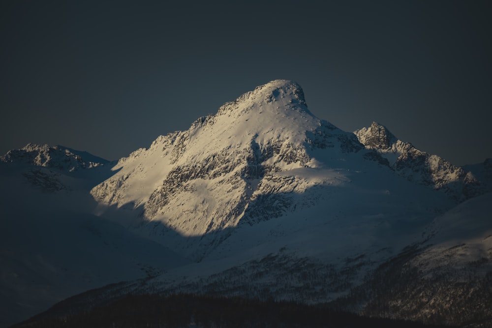 a snow covered mountain with a dark sky in the background