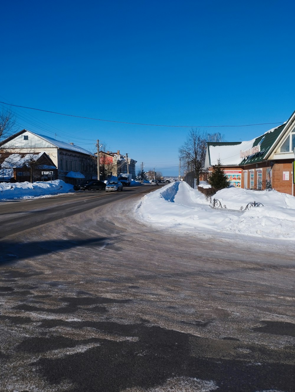 eine Straße mit Schnee auf dem Boden und Häusern im Hintergrund