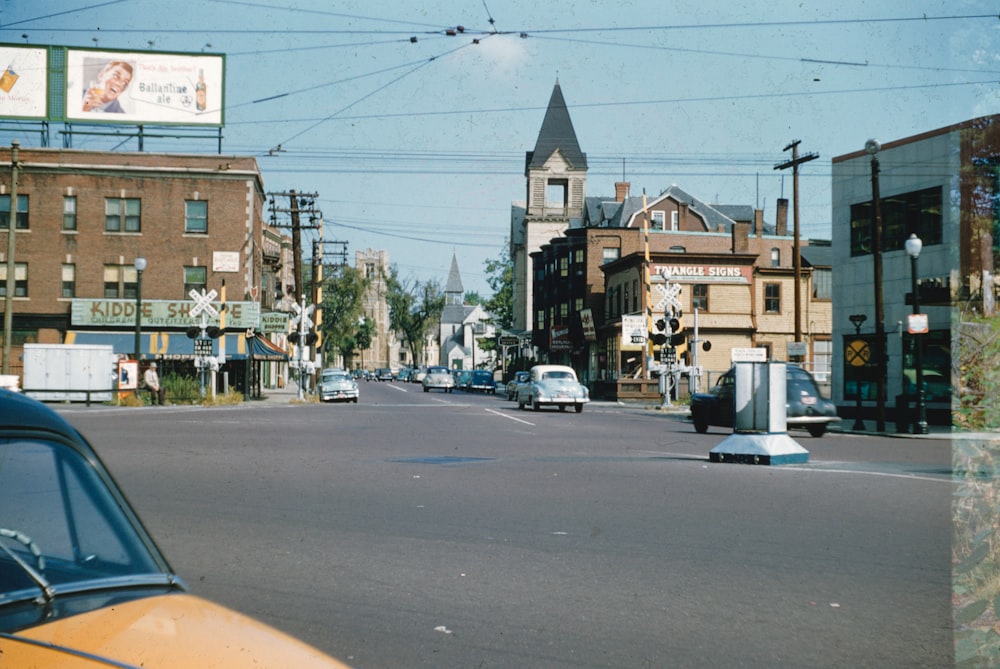 a yellow car driving down a street next to tall buildings