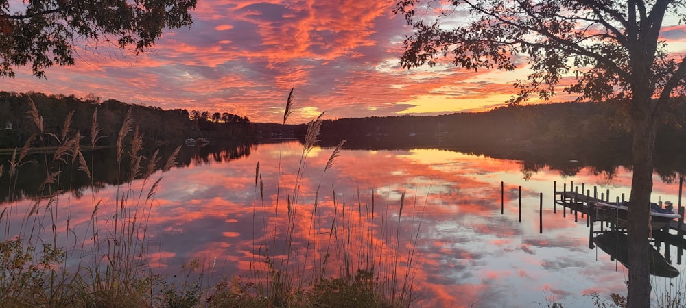 a beautiful sunset over a lake with a dock in the foreground