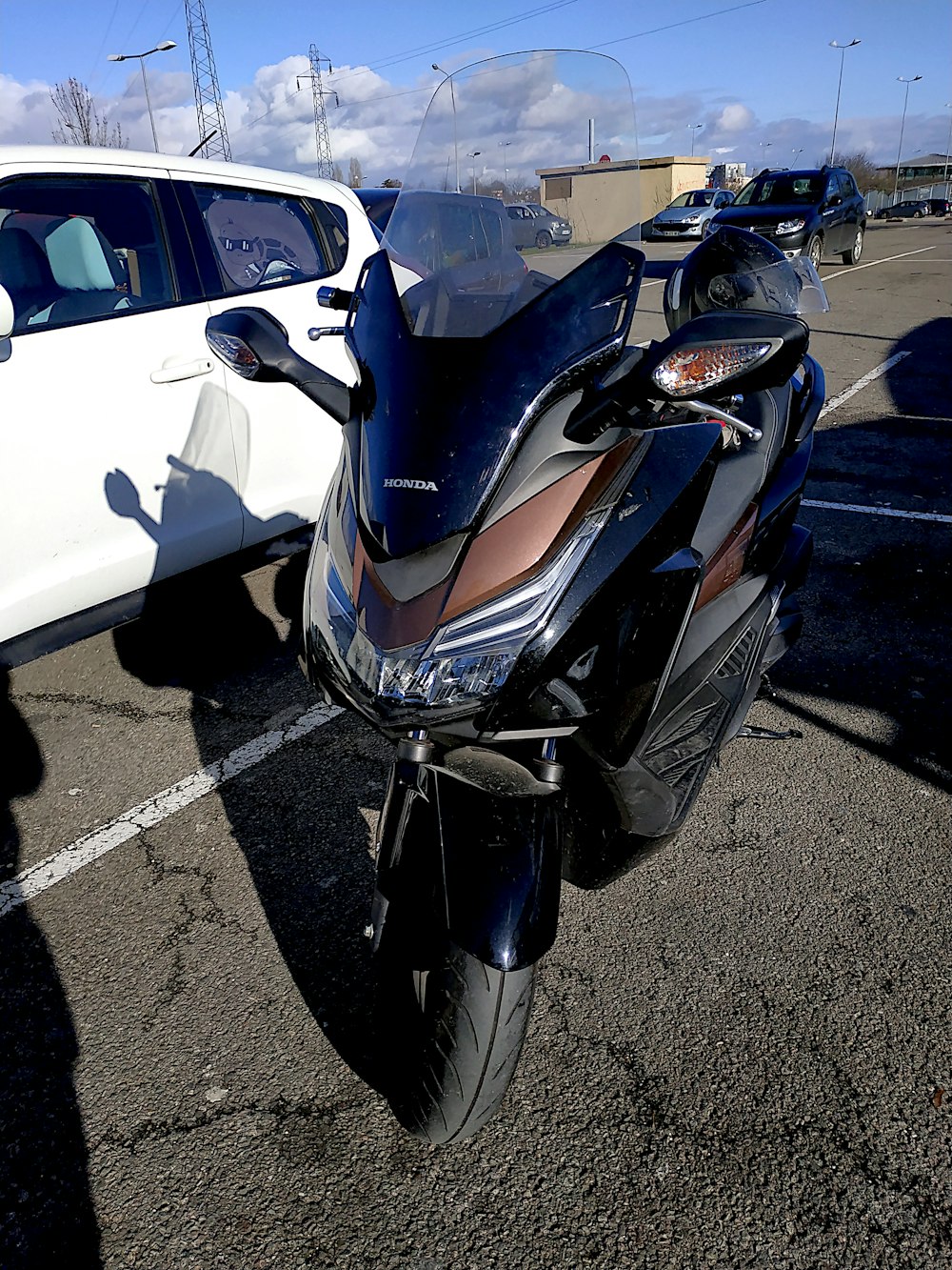 a motorcycle parked in a parking lot next to a white car