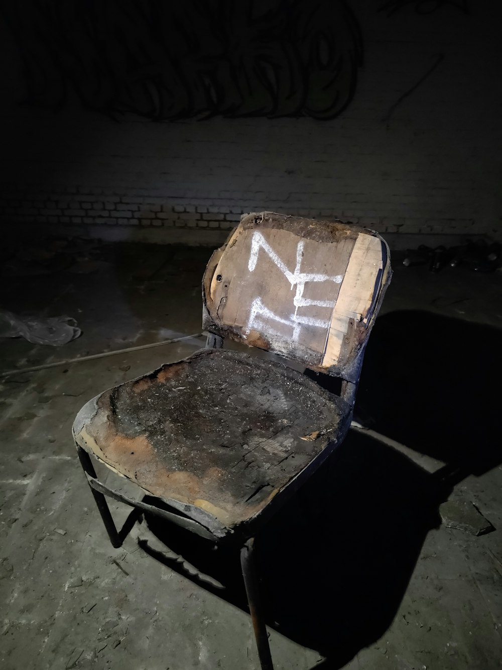 an old chair with graffiti on it in a dark room