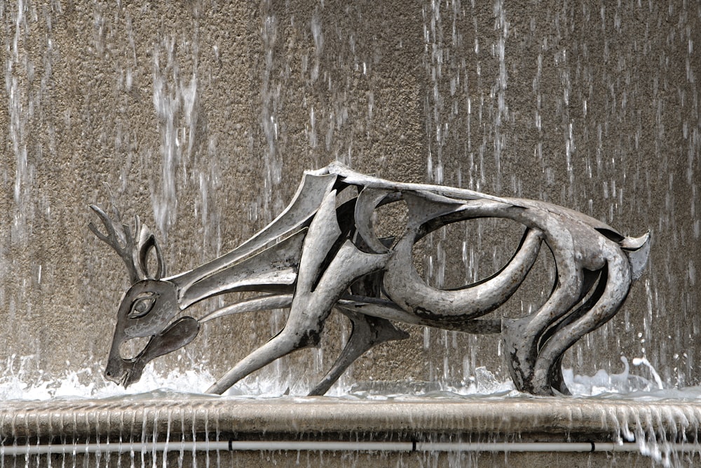 une statue d’un cerf devant une fontaine