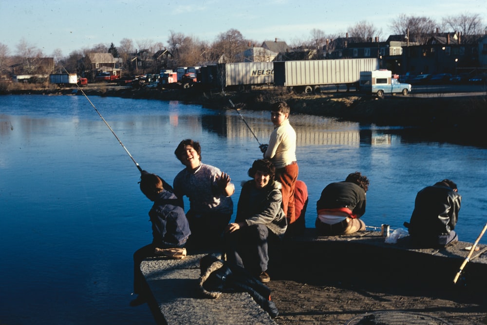 a group of people sitting on a dock fishing