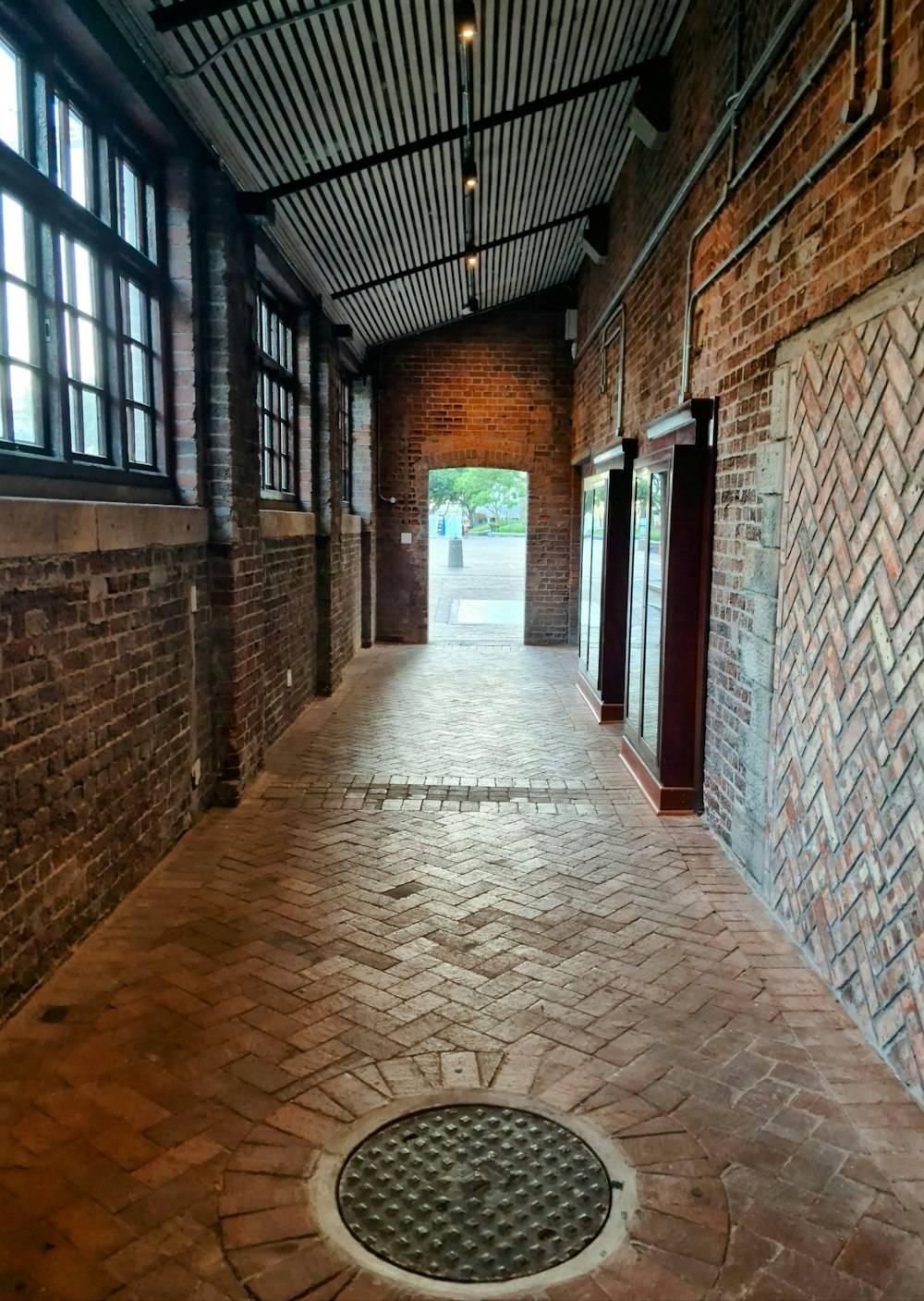 a brick walkway with a manhole in the middle of it