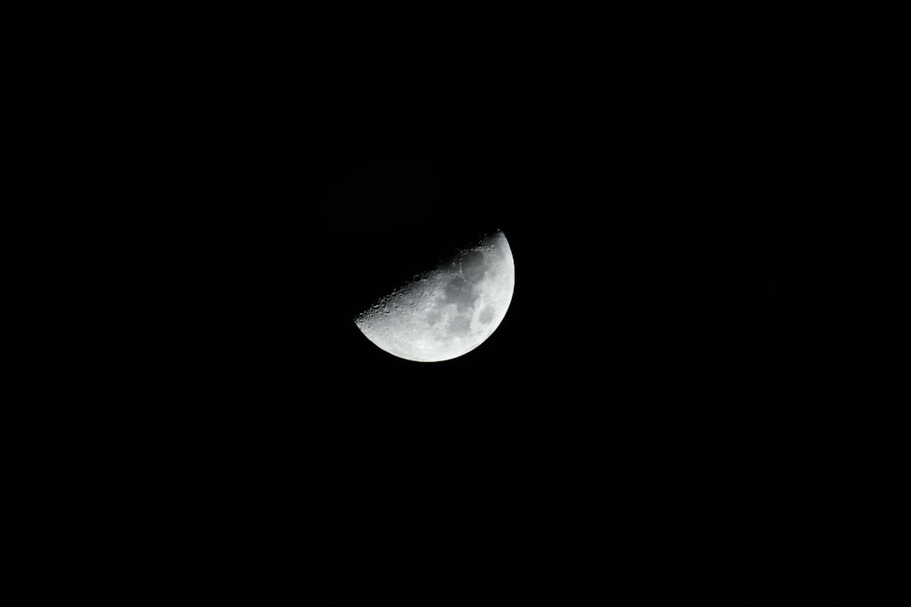 a half moon is seen in the dark sky