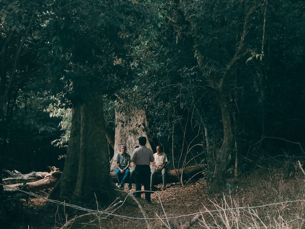 a group of people sitting on a log in the woods