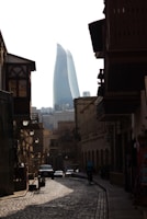 a cobblestone street in a city with a tall building in the background