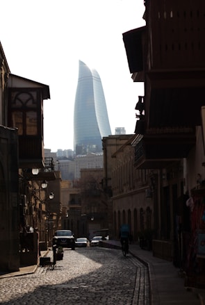 a cobblestone street in a city with a tall building in the background