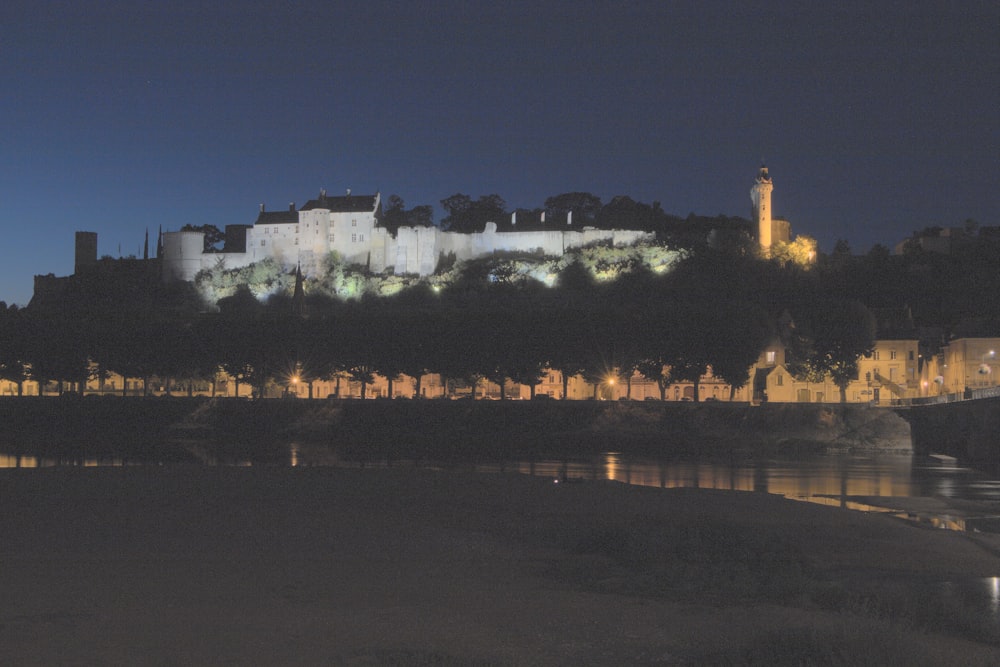 a castle lit up at night with a body of water in front of it
