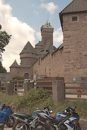 three motorcycles are parked in front of a castle
