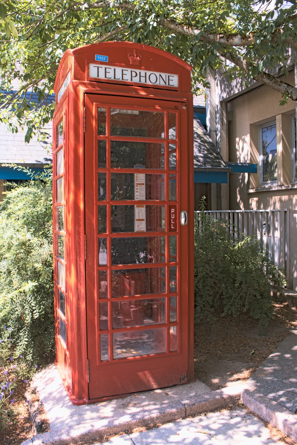 a red telephone booth sitting on the side of a road