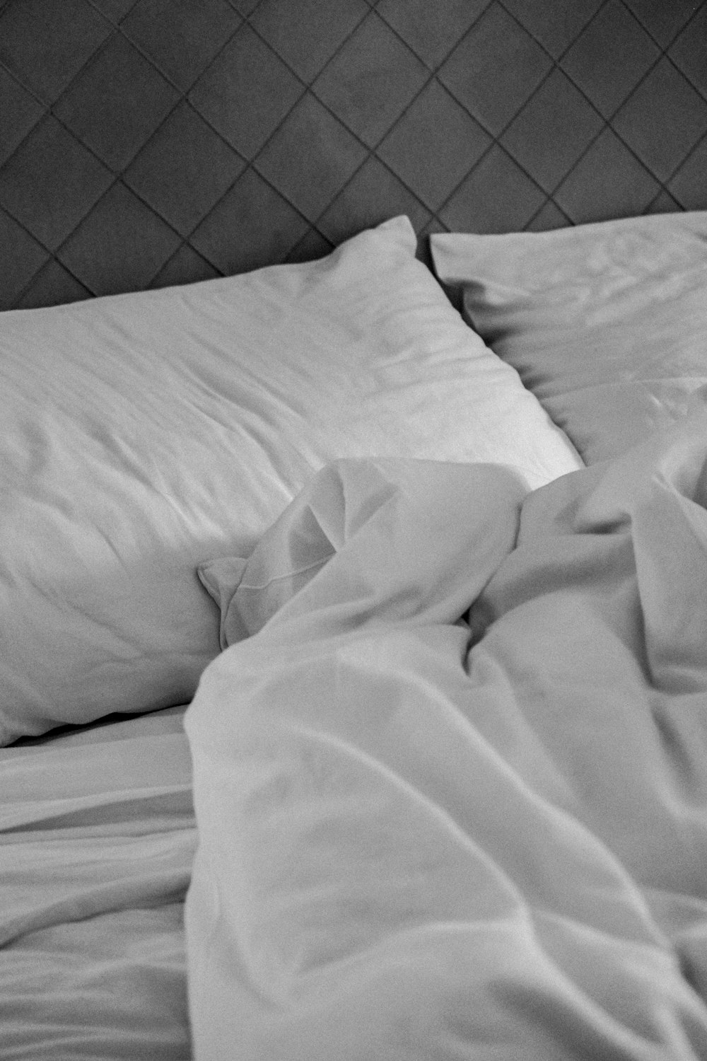 a black and white photo of a bed with white sheets