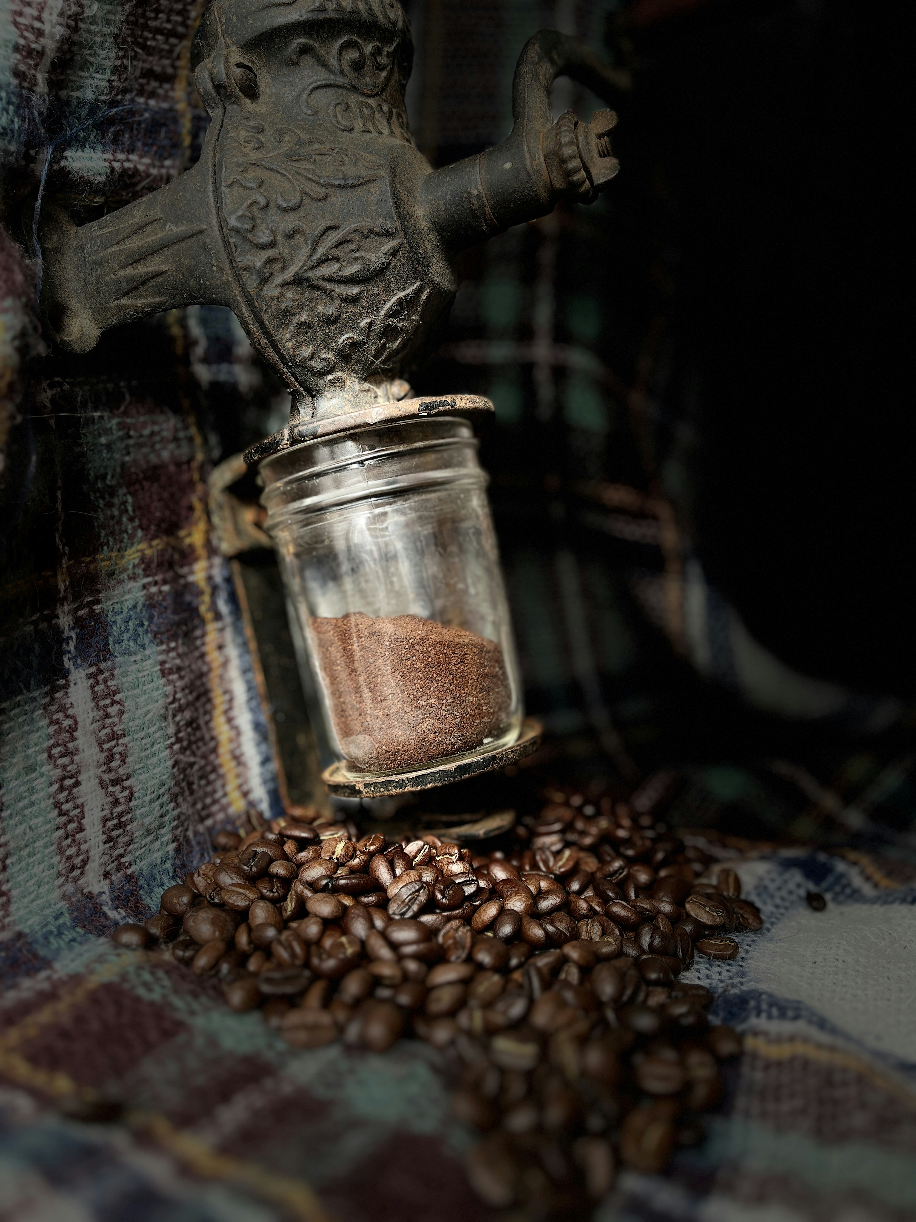 a glass jar filled with coffee beans sitting on top of a plaid blanket