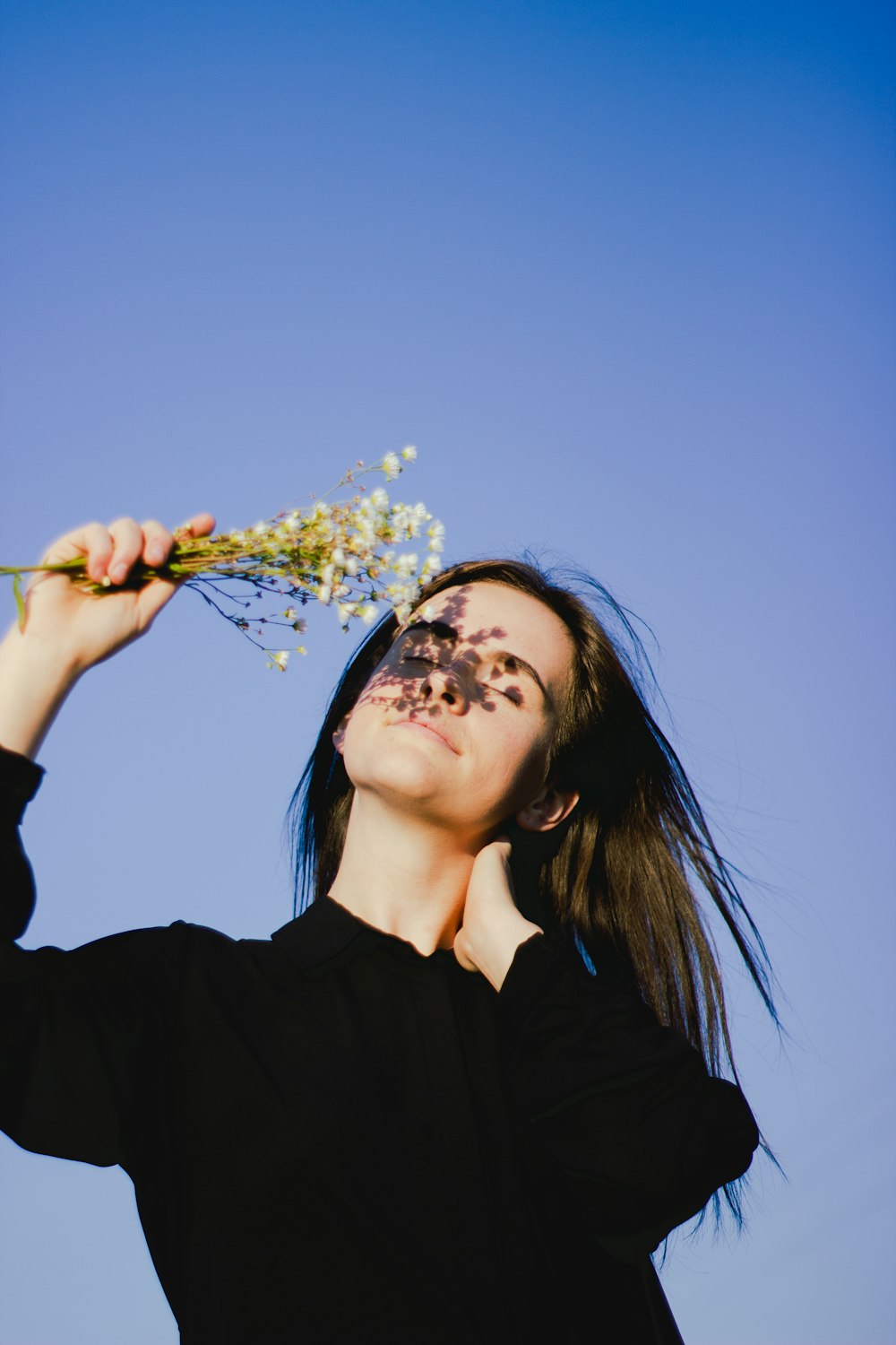 a woman holding a bunch of flowers up to her face