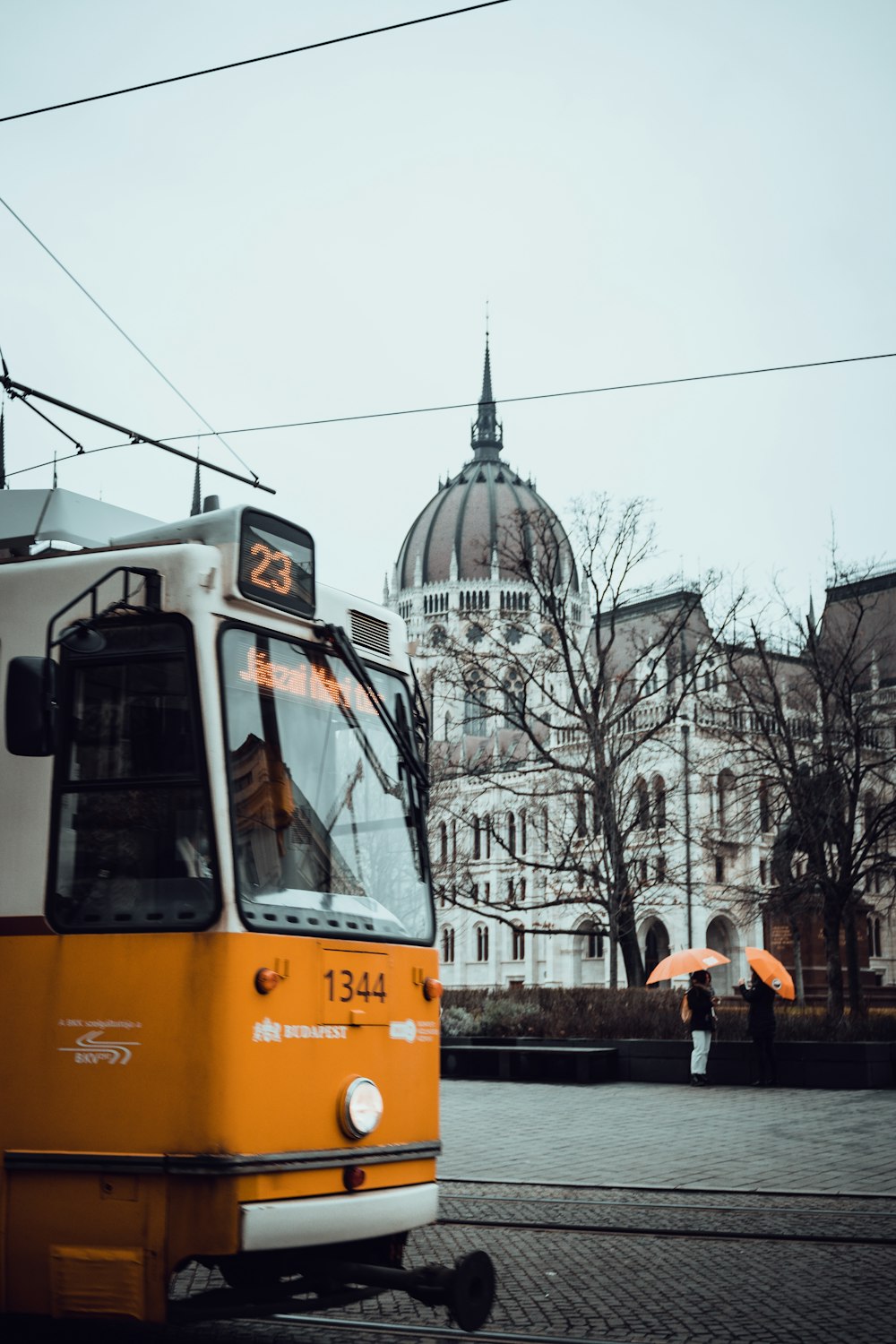 a yellow and white bus on street next to a building