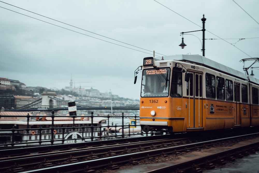 a yellow and white train traveling down train tracks