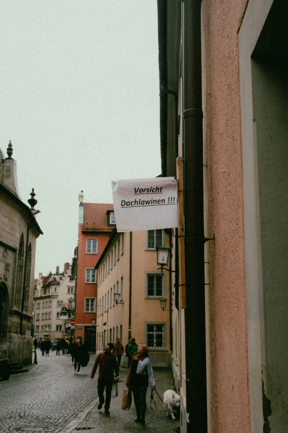 a group of people walking down a cobblestone street