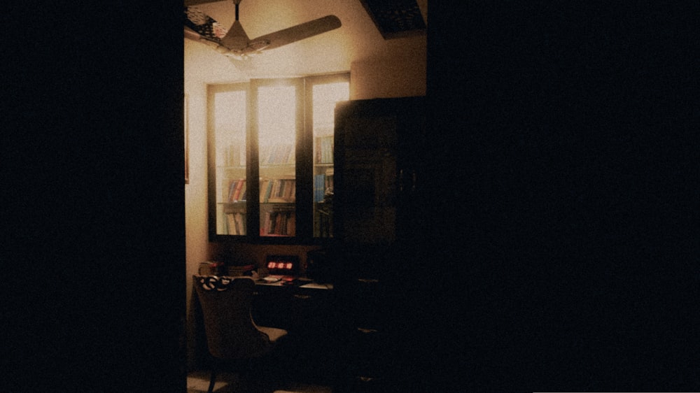a dark room with a window and a fan
