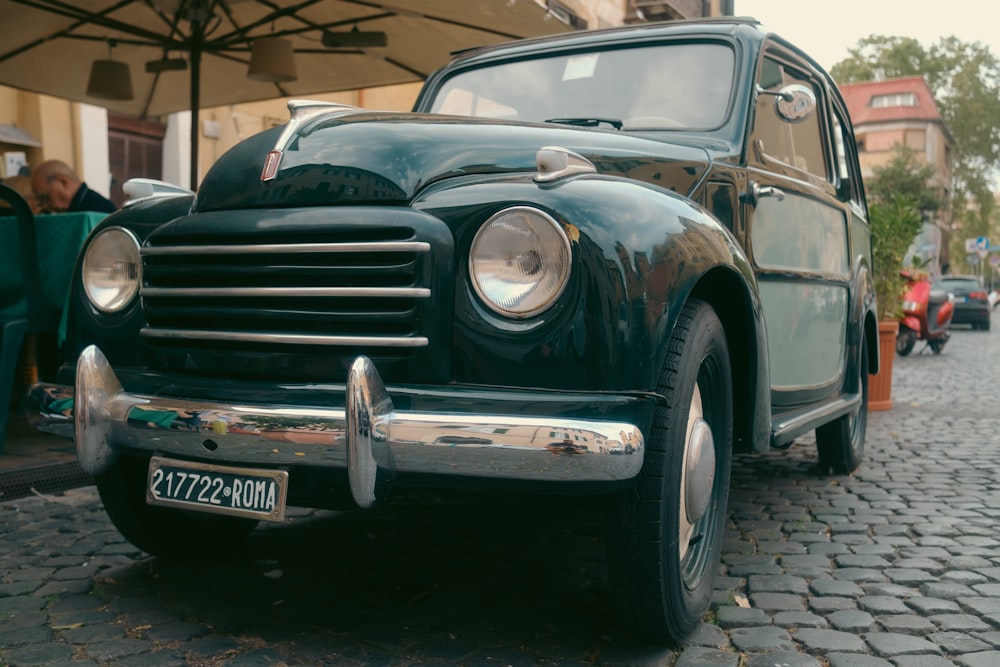 an old car parked on a cobblestone street