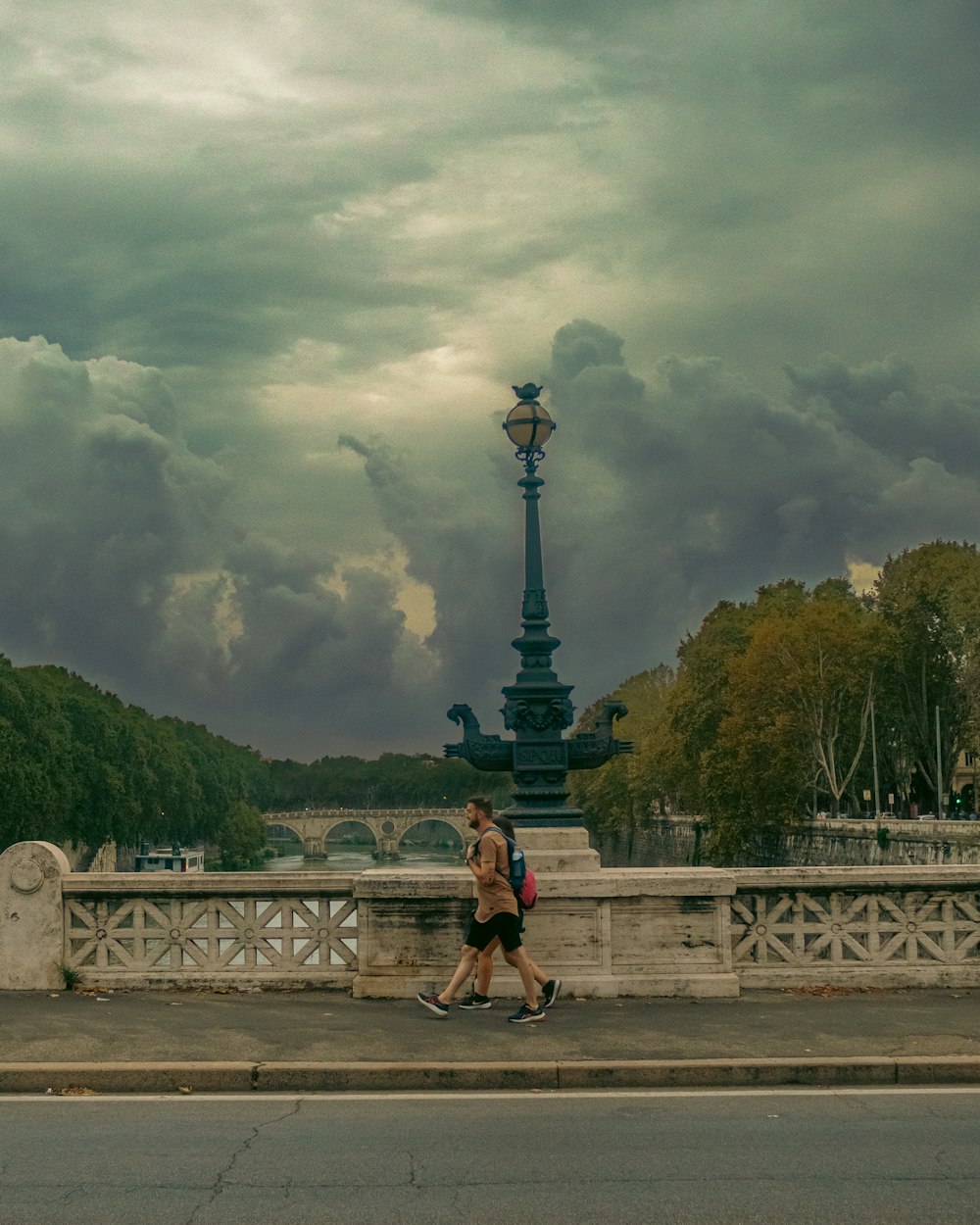 Un homme traversant un pont sous un ciel nuageux