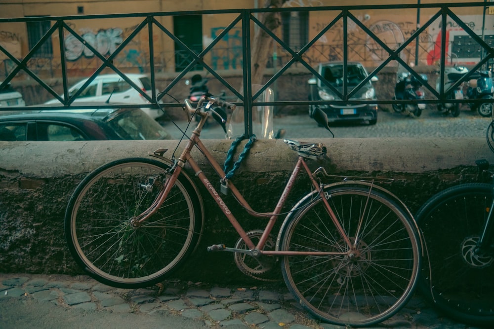a bicycle parked next to a wall on a city street