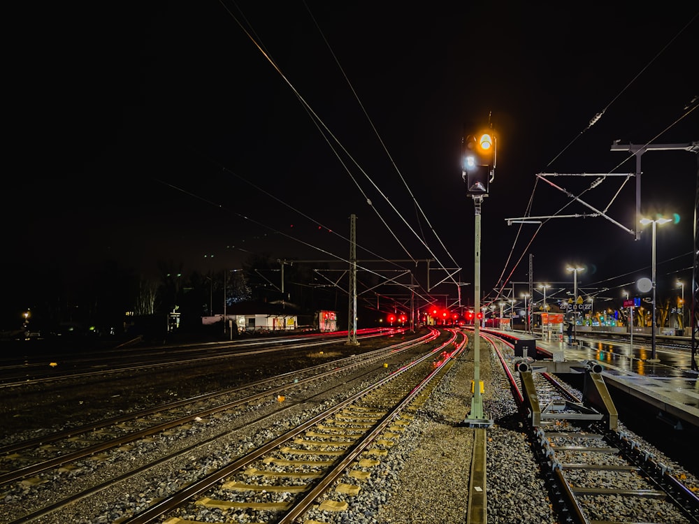 una vía de tren con un semáforo en rojo por la noche