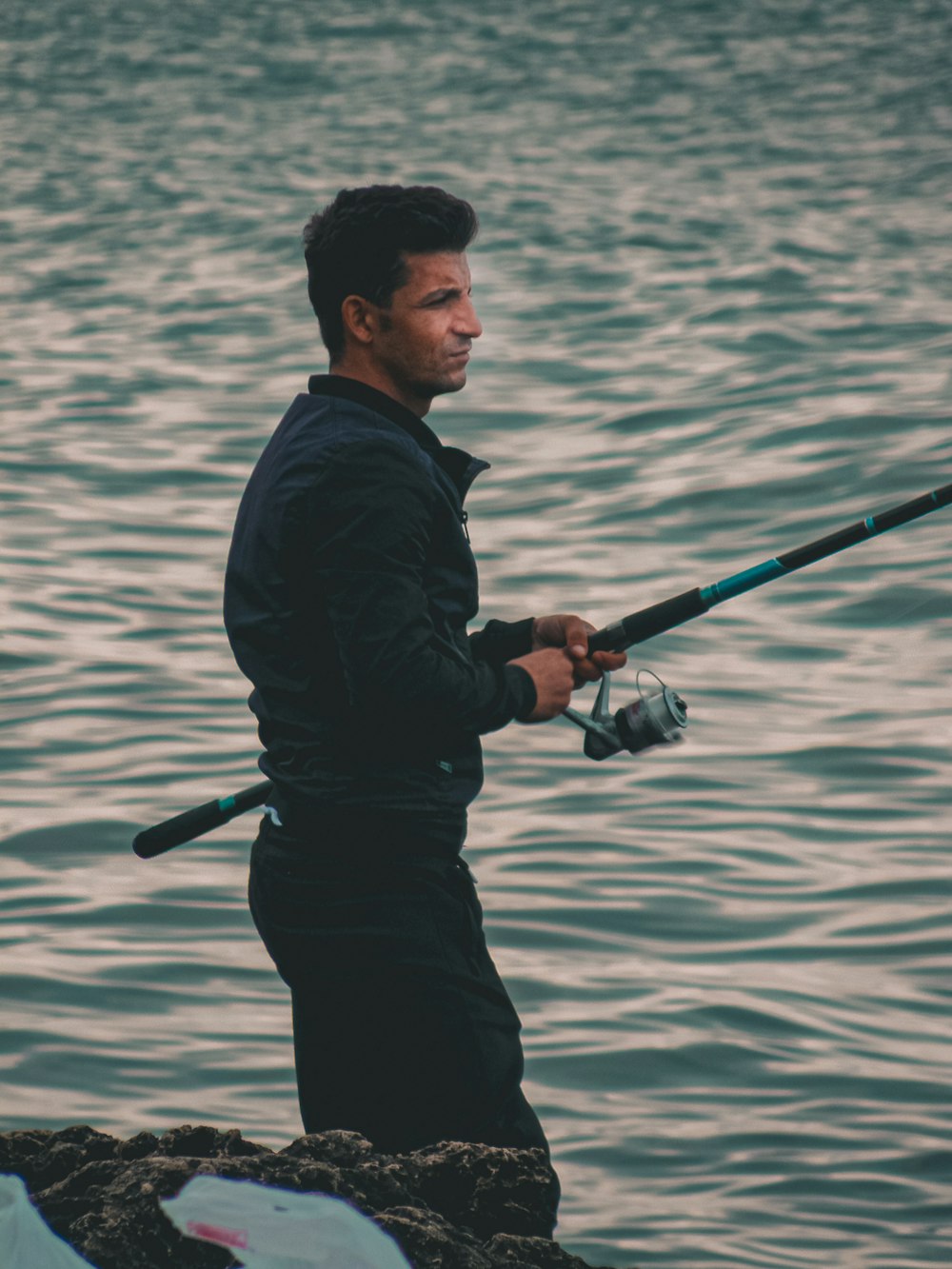 a man standing on a rock with a fishing rod