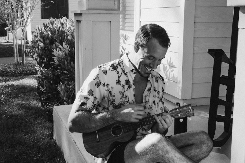 a man sitting on a porch playing a guitar