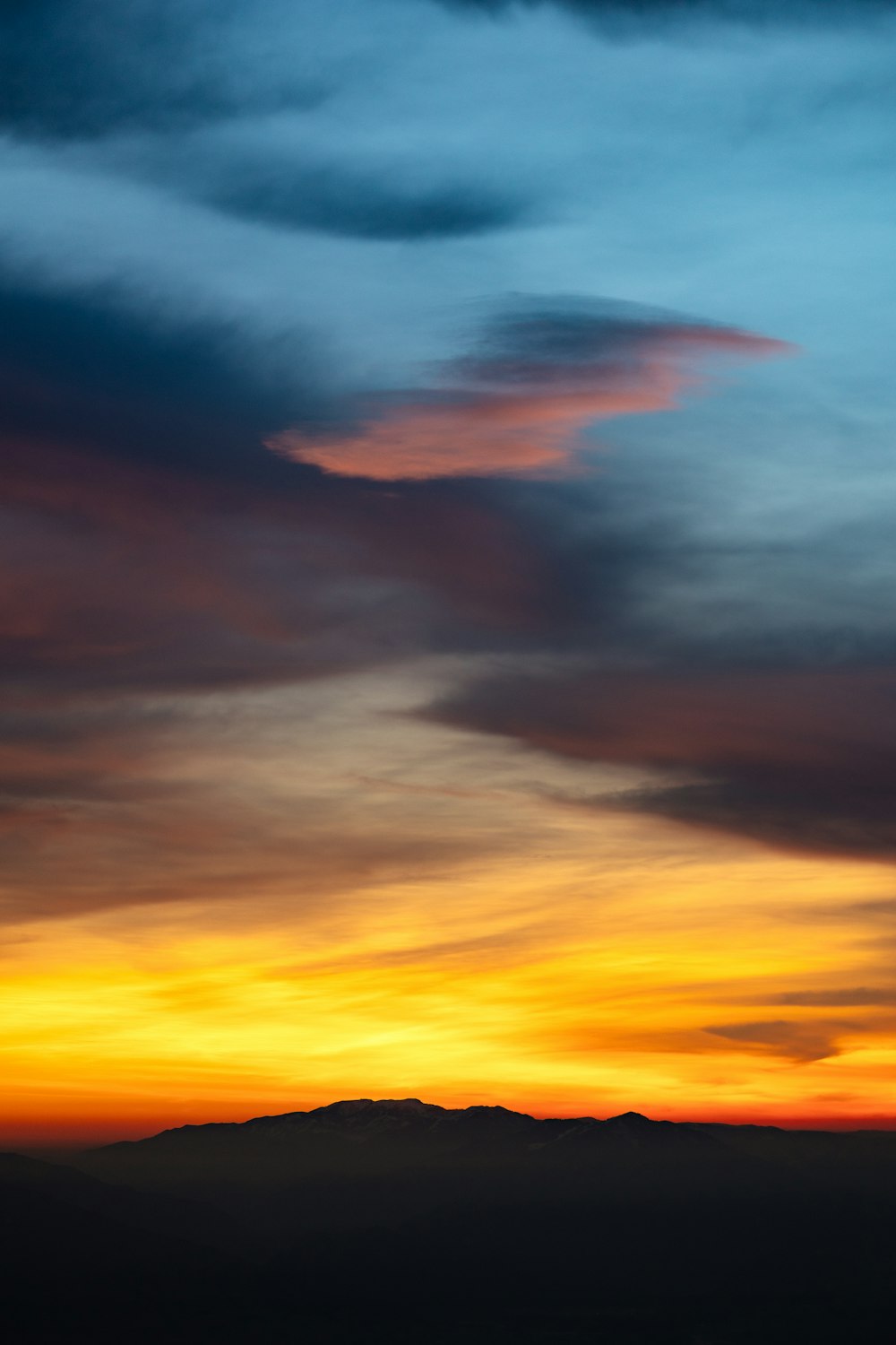 a plane flying in the sky with a sunset in the background