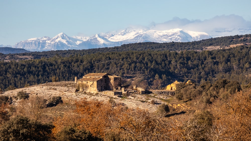 an old building on a hill with mountains in the background