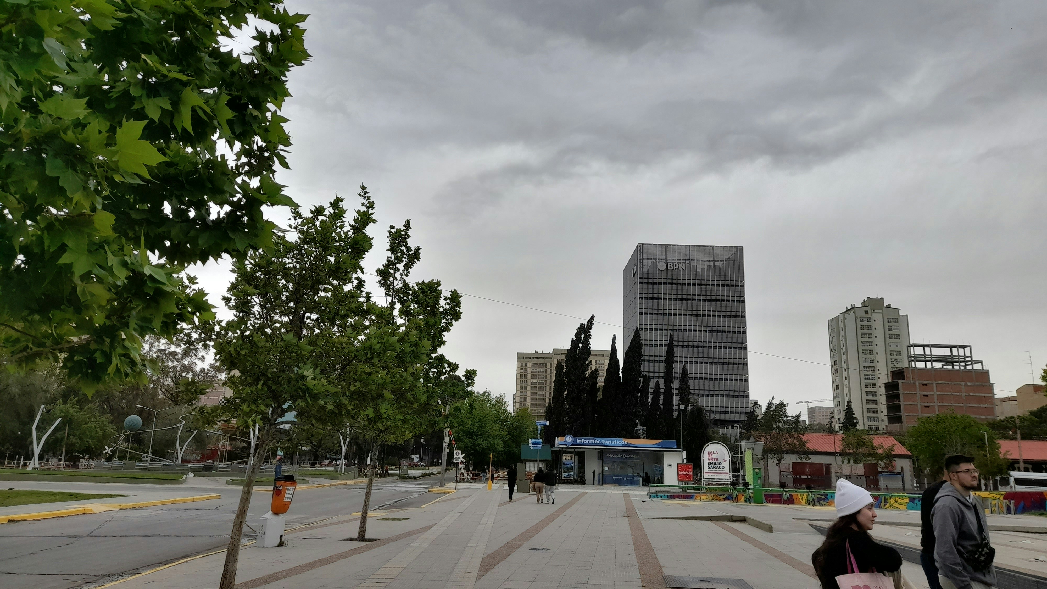 a couple of people walking down a street next to tall buildings
