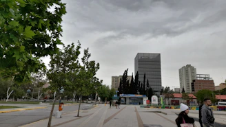 a couple of people walking down a street next to tall buildings