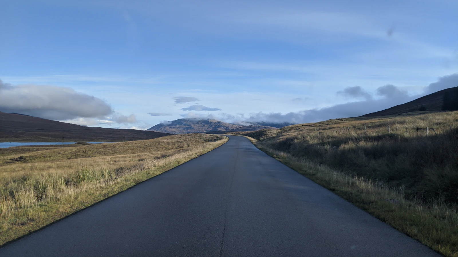 A single-lane road crosses open Highland country
