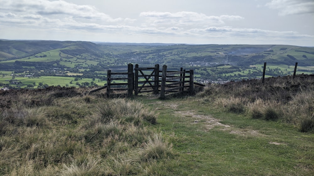 a wooden gate on top of a grassy hill