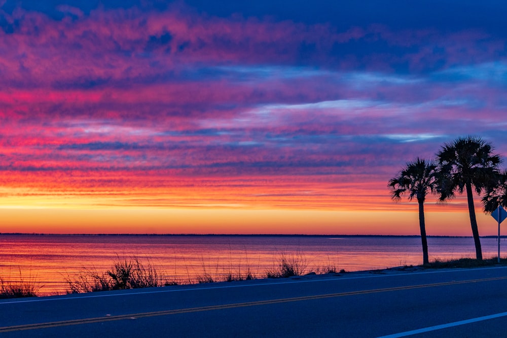 a beautiful sunset over the ocean with palm trees