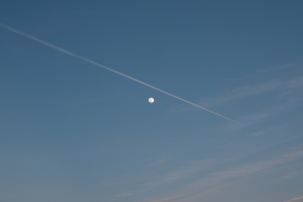 a plane flying in the sky with a moon in the background