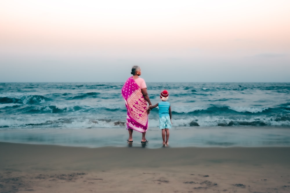 um homem e uma menina em pé em uma praia