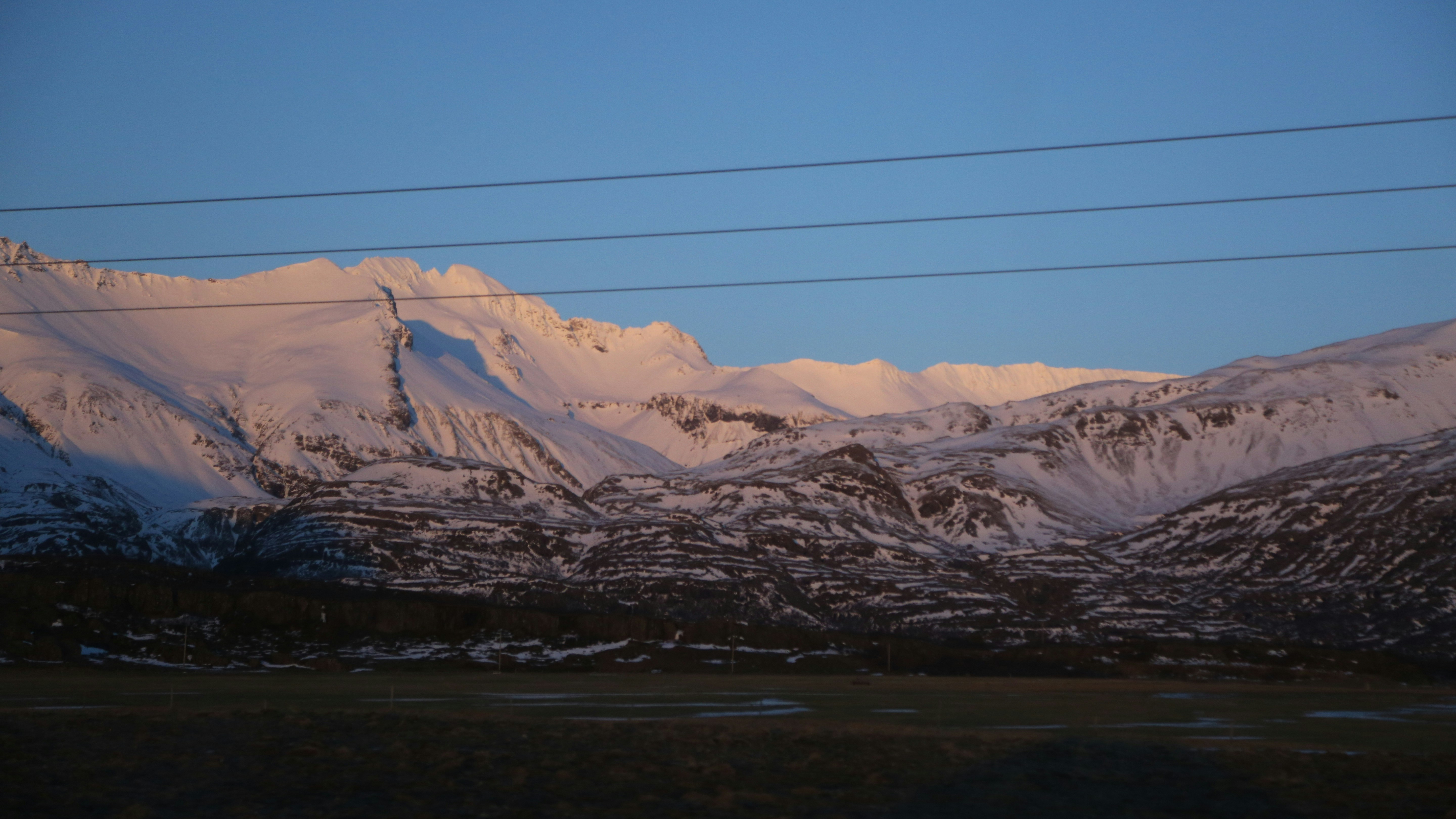 a snowy mountain range with power lines in the foreground