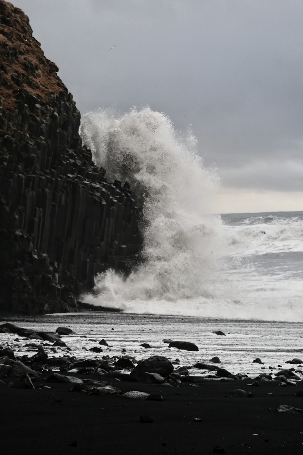a large wave crashing into a rocky beach