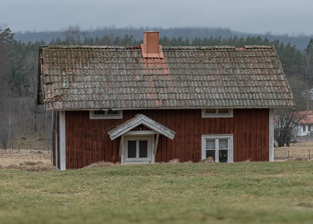 a red barn with a brown roof and a sheep grazing in a field