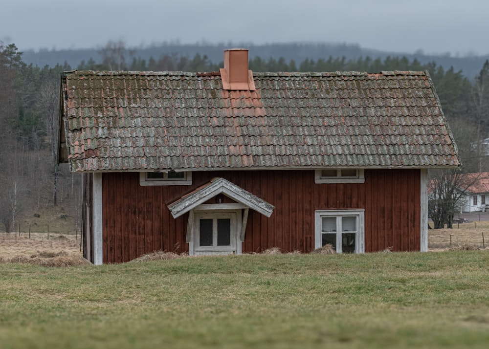 un fienile rosso con il tetto marrone e una pecora al pascolo in un campo