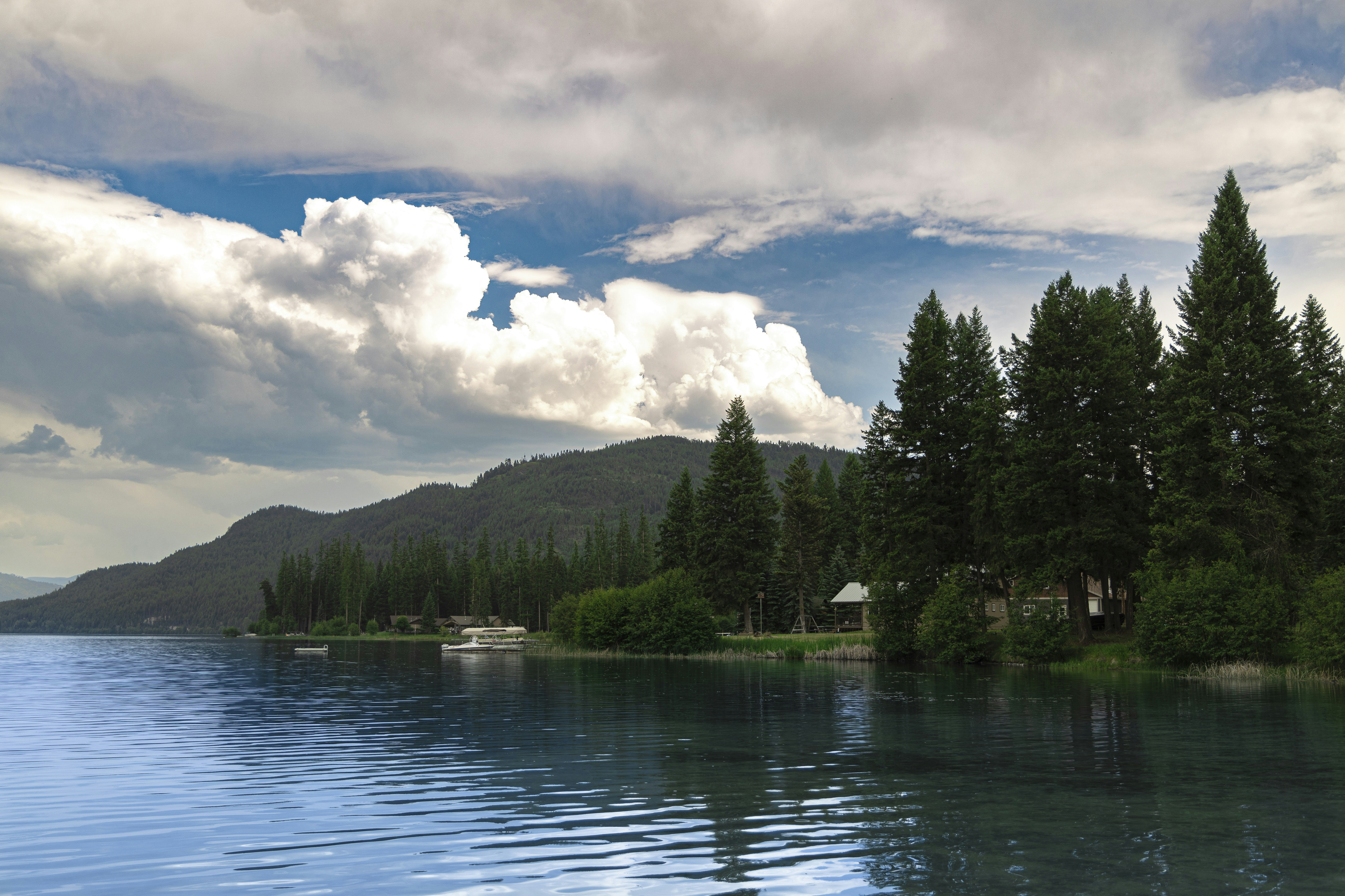 un plan d’eau entouré d’arbres et de nuages