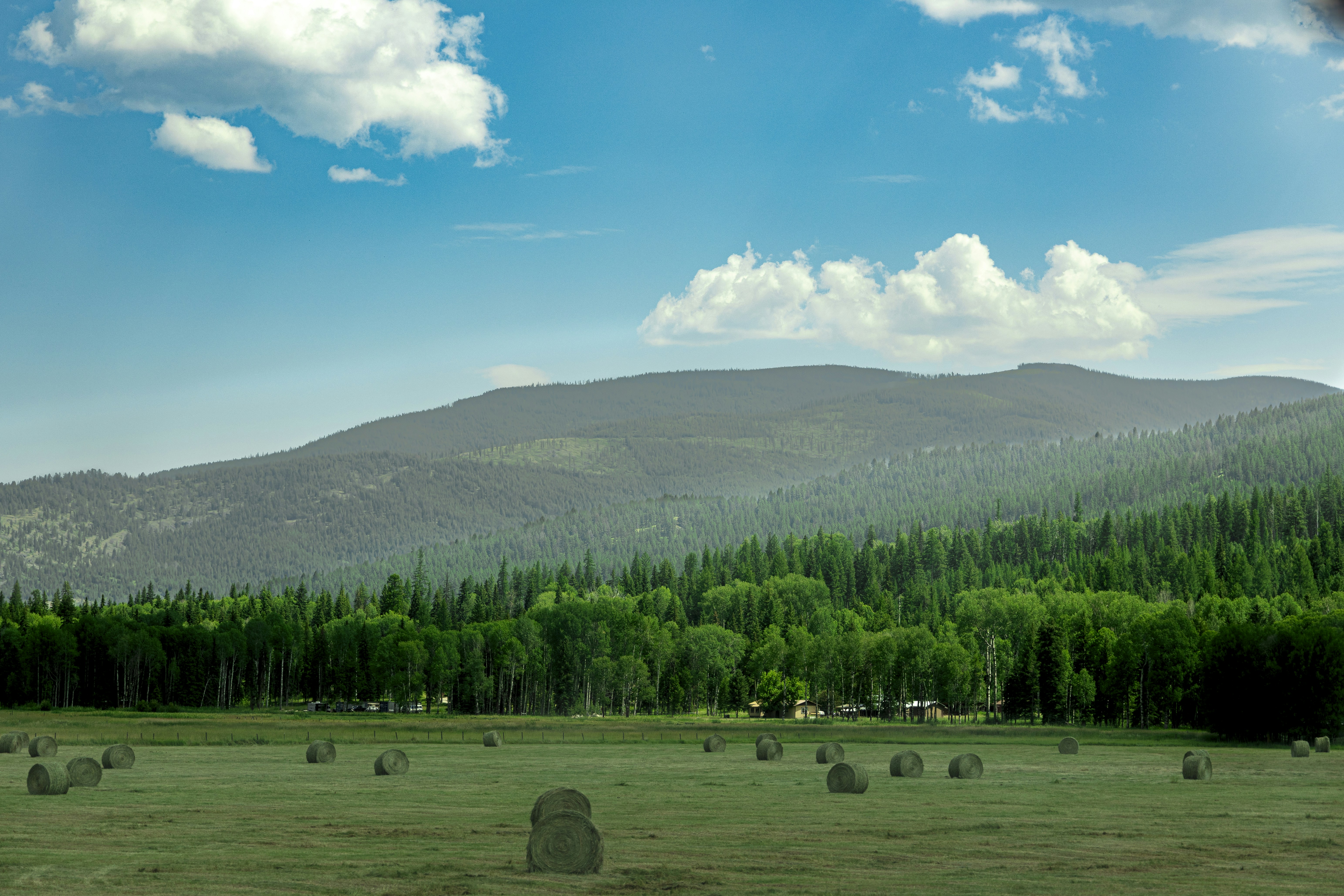 A field with bales of hay in the foreground and a mountain in the photo