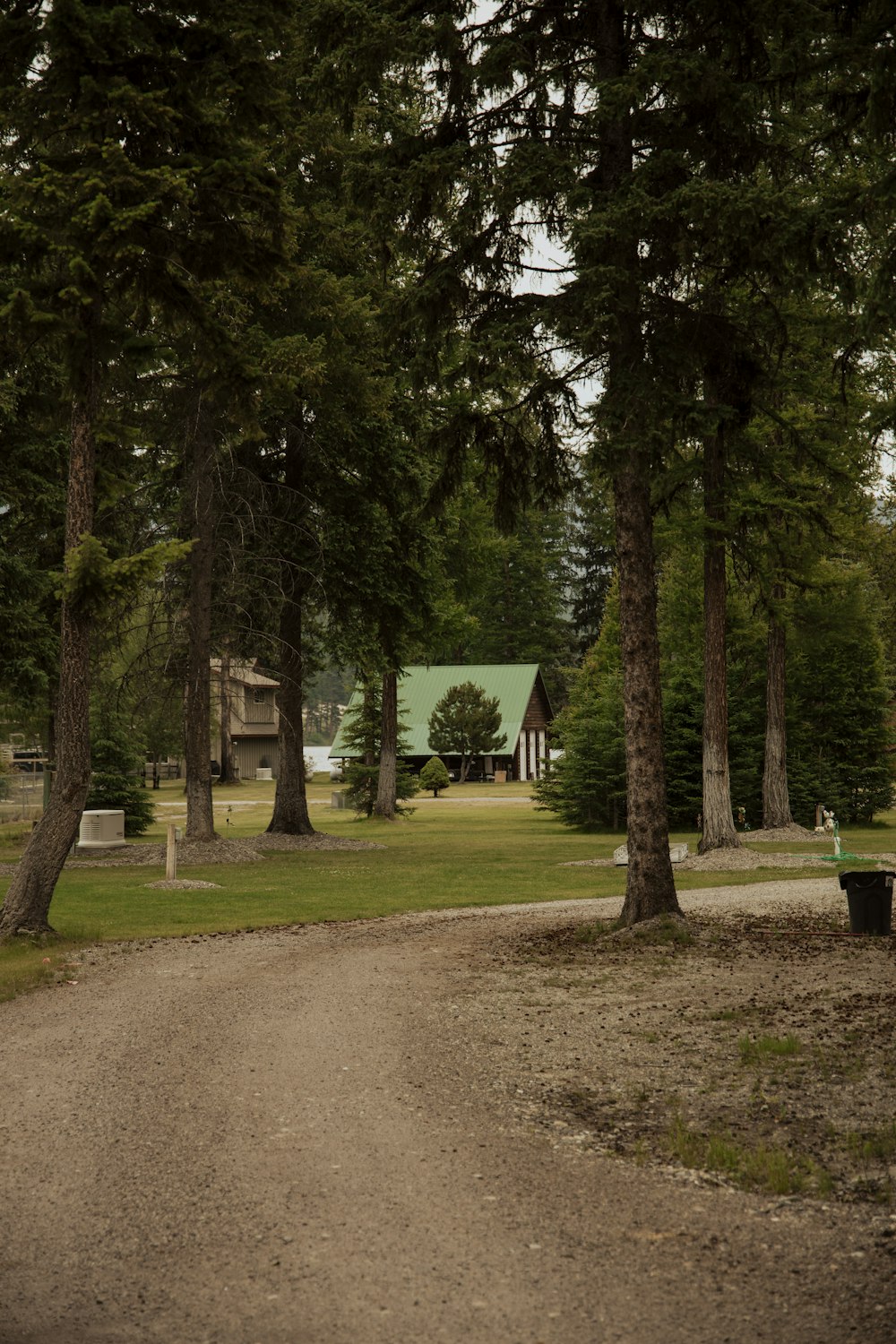 a dirt road in a park with a house in the background