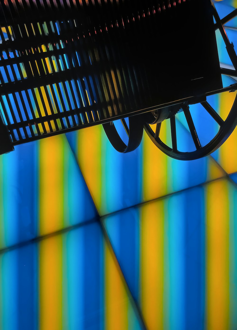 a black bench sitting under a colorful wall